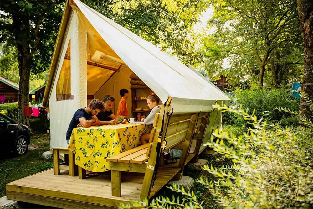 Famille sur la terrasse de leur lodge au camping Le Pré Morjal à Ispagnac